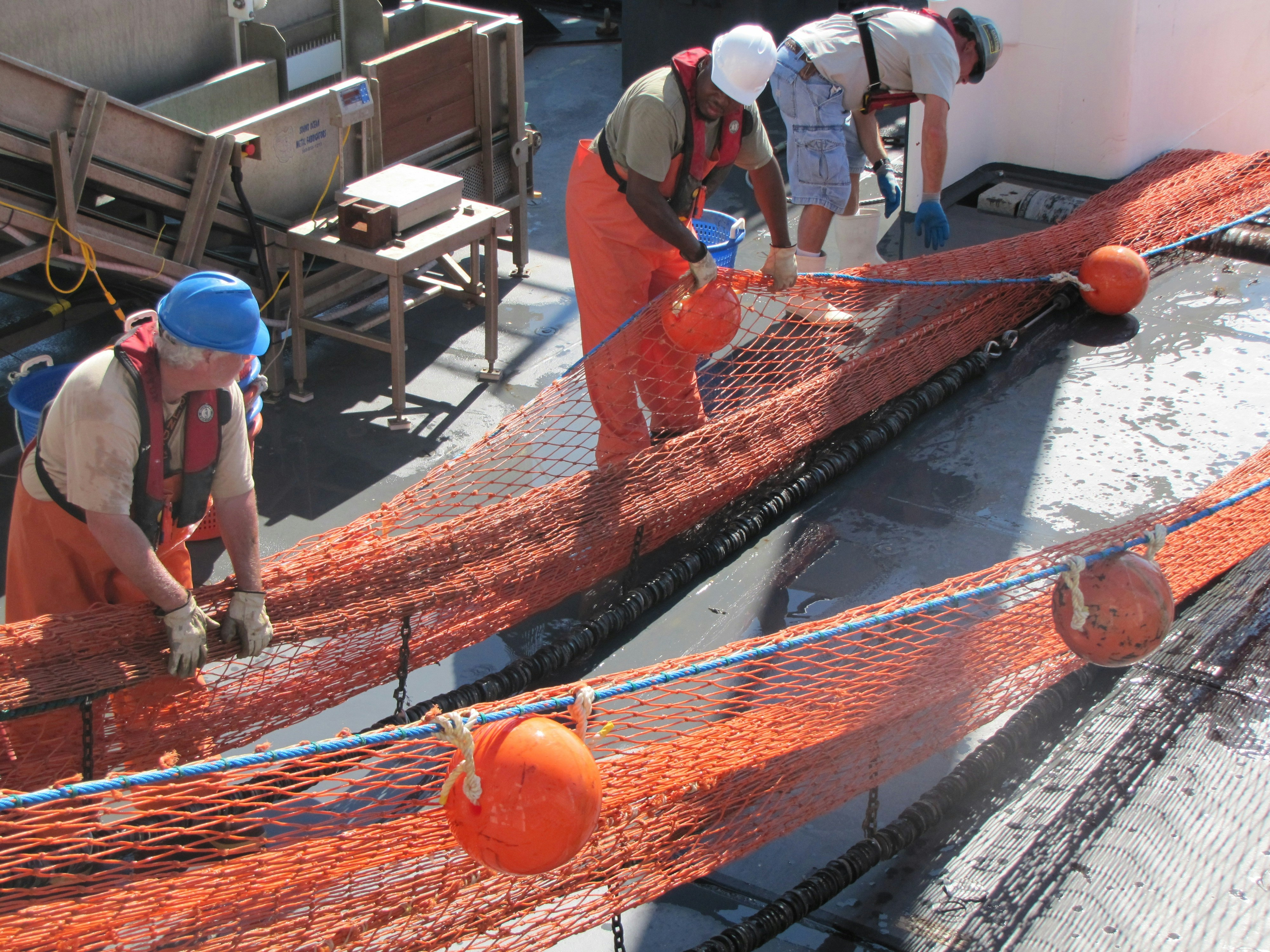 Workers handling orange marine safety net
